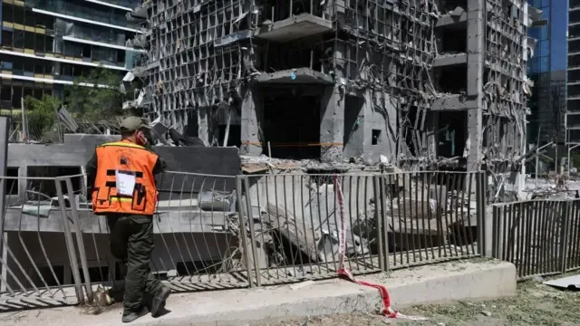 A members of Israel's Home Front Command stands near the site of an Iranian missile strike in a residential area in Ramat Gan