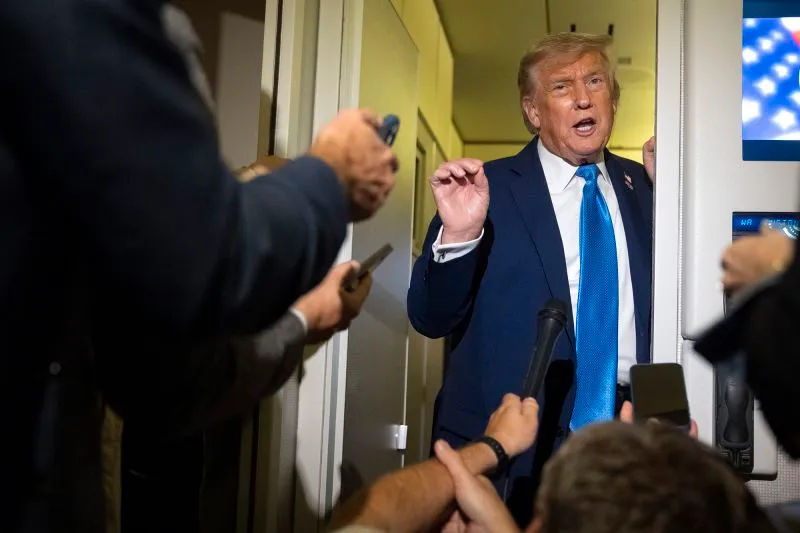 President Donald Trump speaks with reporters while flying aboard Air Force One en route from Calgary, Canada to Joint Base Andrews, Md., late on Monday.