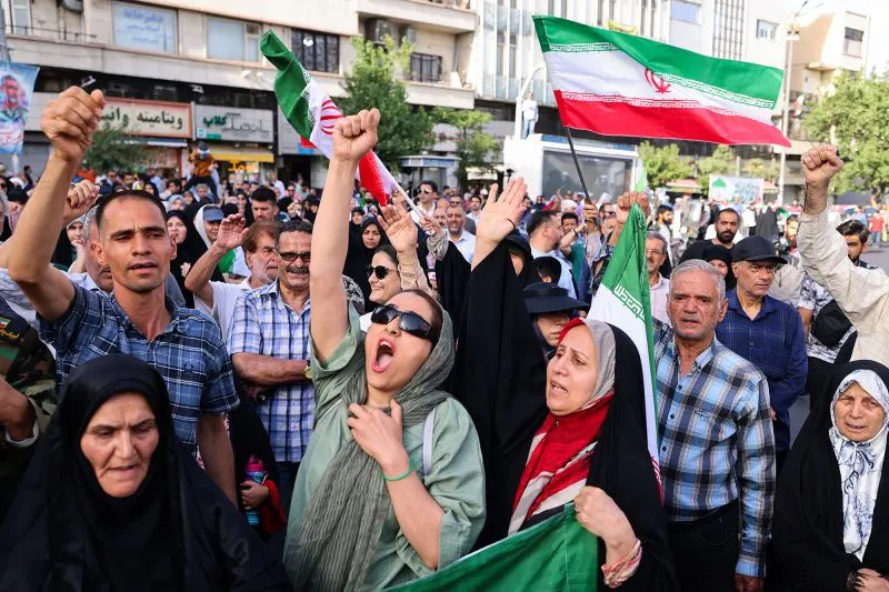 Iranians lift flags and chant during a rally protesting the US attack on Iran in Enghelab Square in Tehran, Iran, on Sunday.