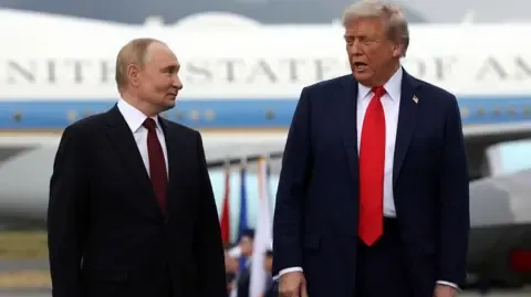 Getty Images Donald Trump and Vladimir Putin stand side by side and speak as they pose for photos after their arrival for the US-Russia summit 