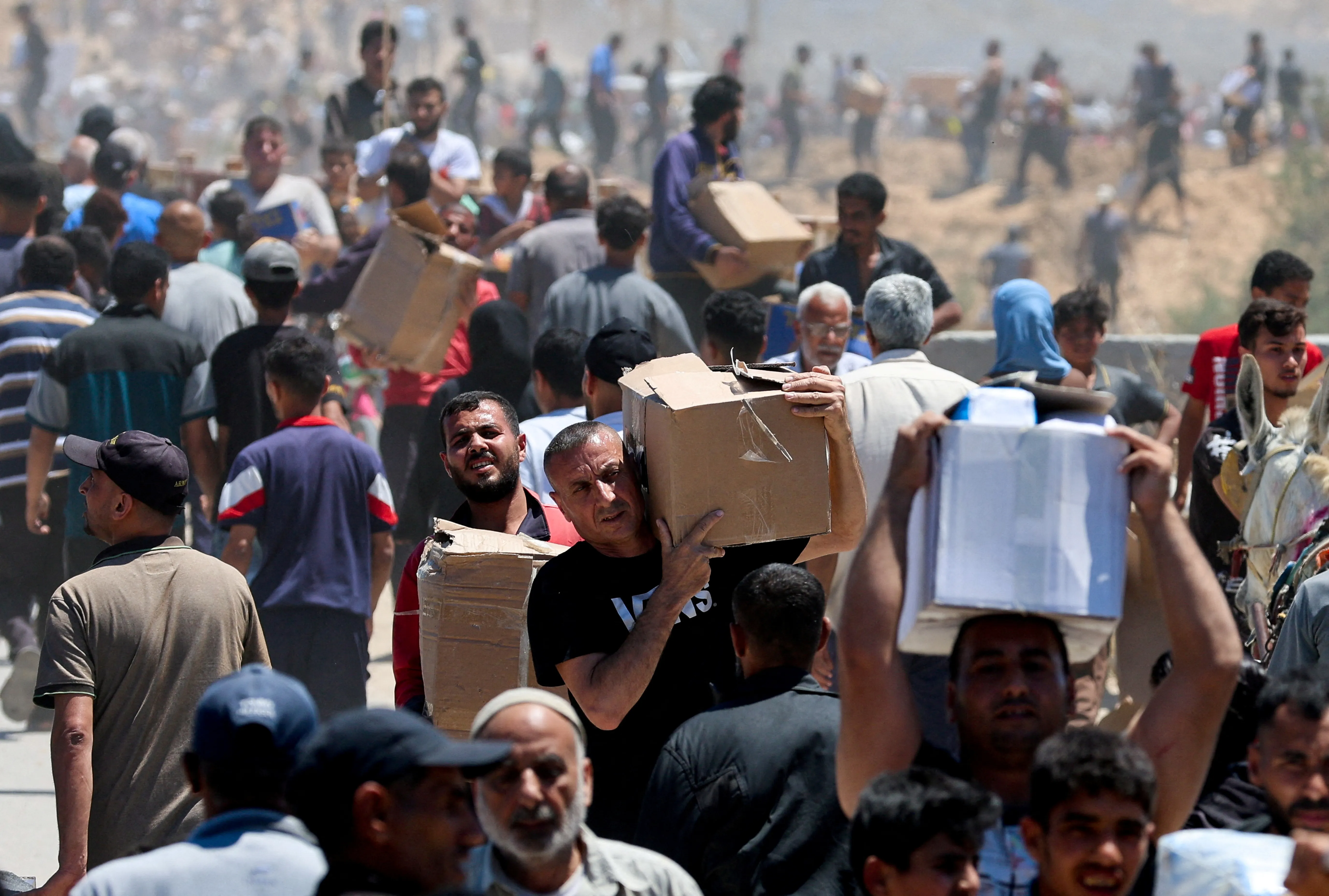 Palestinians carry aid supplies which they received from the U.S.-backed Gaza Humanitarian Foundation, in the central Gaza Strip, May 29, 2025. REUTERS/Ramadan Abed REFILE - CORRECTING LOCATION FROM "NEAR AN AREA OF GAZA KNOWN AS THE NETZARIM CORRIDOR" TO "IN THE CENTRAL GAZA STRIP".