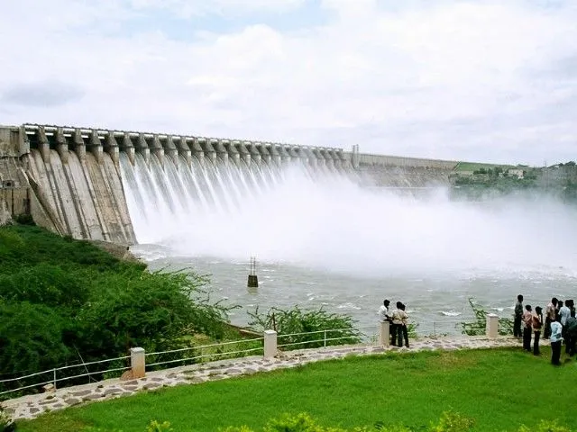 This may contain: people standing in front of a large dam with water pouring out of it's gates