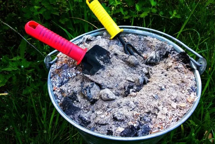 This may contain: a bucket filled with sand and two plastic shovels sitting on top of it in the grass