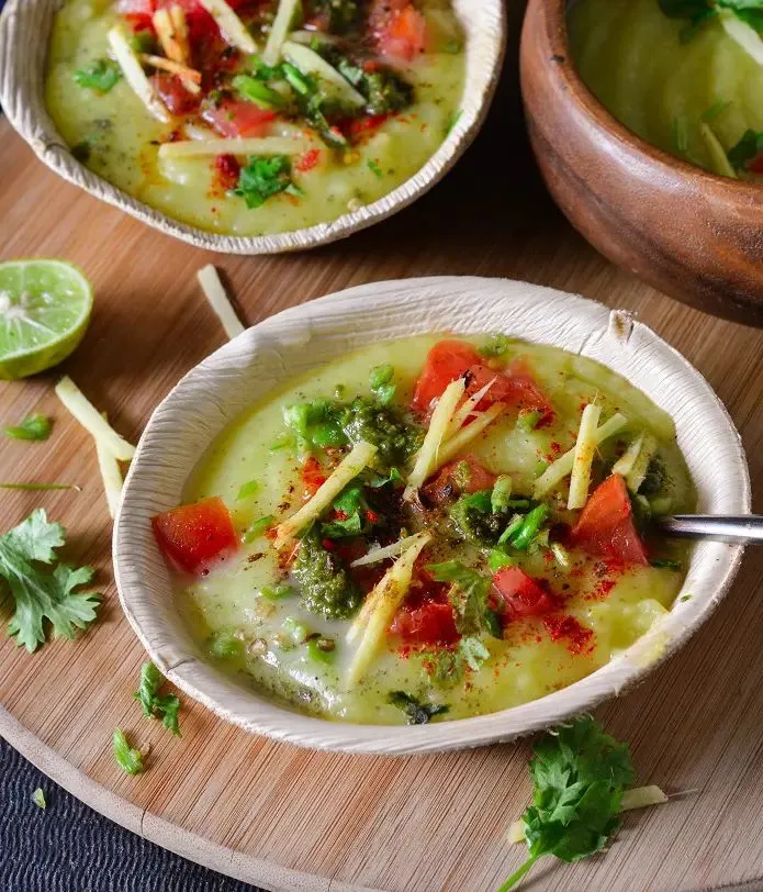 This may contain: two bowls filled with soup on top of a wooden tray next to lime wedges