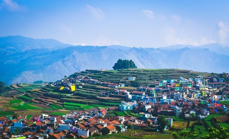 This may contain: a village on top of a hill with mountains in the background