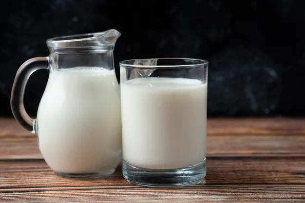 Free photo fresh milk in a mug and jug on wooden table.