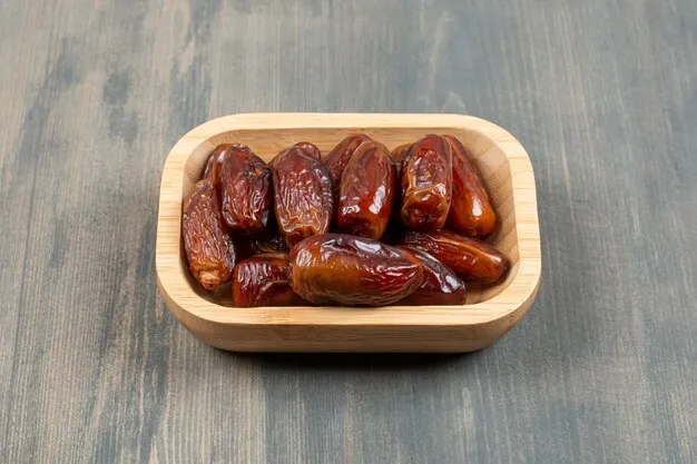 Free photo juicy dates in a wooden plate on a wooden table