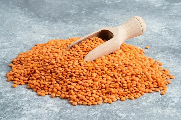 Free photo pile of red lentils on marble surface with wooden spoon.