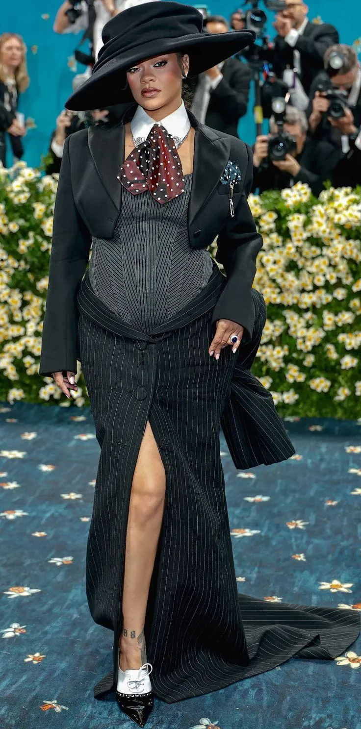 This may contain: a woman in a black hat and dress walking down the runway