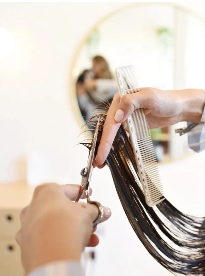 This may contain: a woman is cutting her hair with scissors