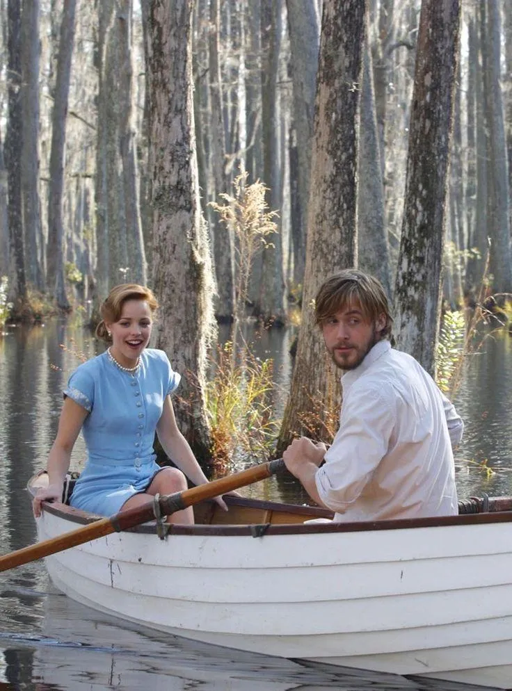 This may contain: a man and woman in a row boat on the water