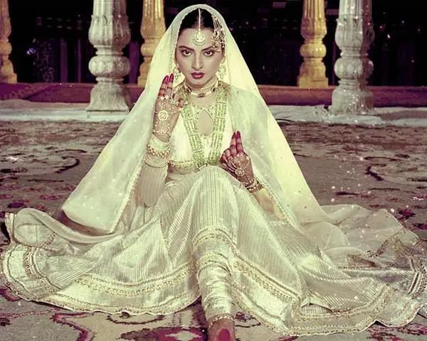 This may contain: a woman sitting on the floor wearing a white dress and veil with her hands up to her face