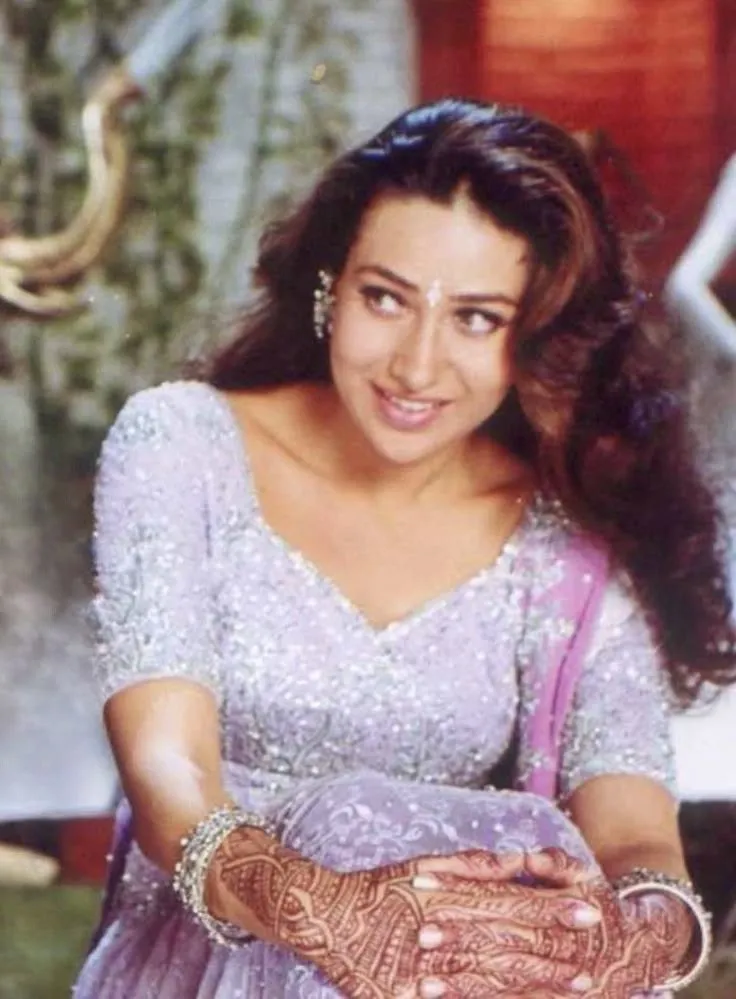 This may contain: an old photo of a woman in a purple dress holding her hands out to the camera