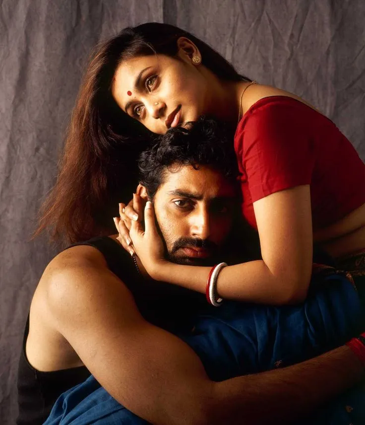 This may contain: two people are hugging each other in front of a gray background and the man is wearing a red shirt