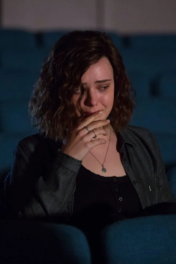 This may contain: a woman is sitting in the dark with her hand on her mouth and looking down