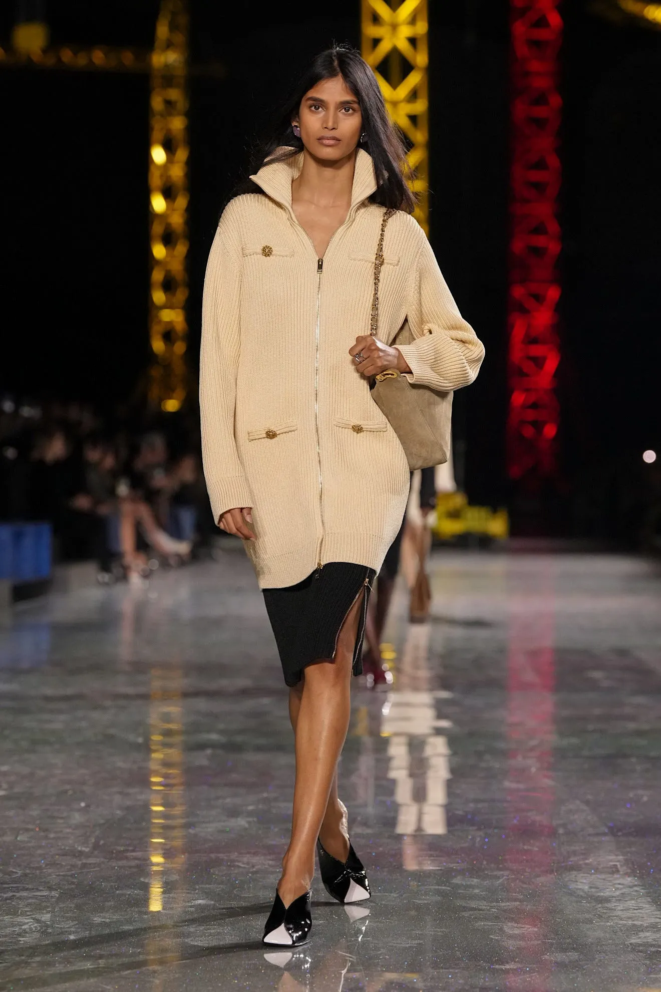 Model walking on a runway wearing a stylish outfit.