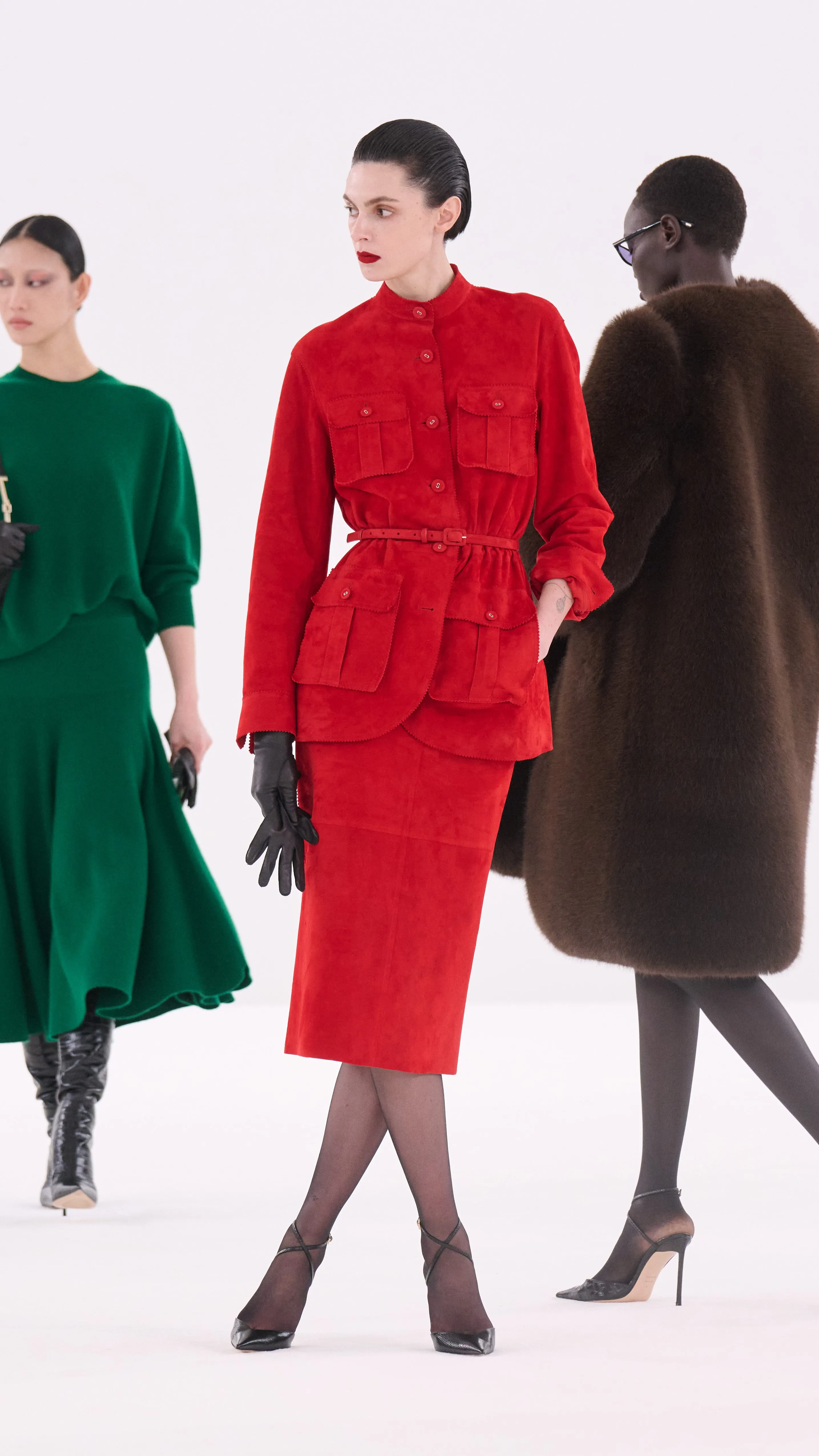 three models showcasing high fashion outfits on a runway