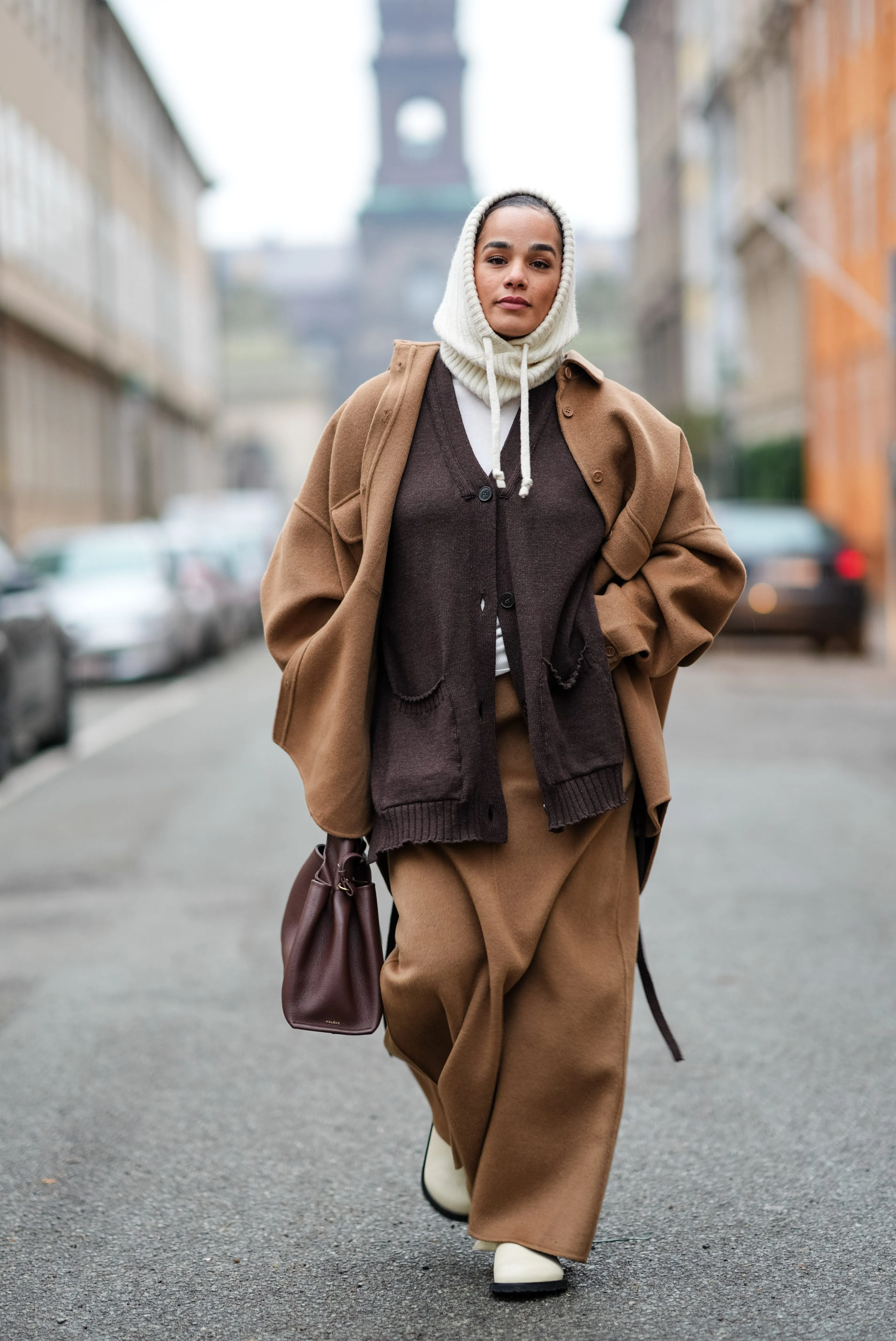 copenhagen, denmark january 30: a guest wears a white ribbed wool hood, a brown full look, an oversized jacket , a cardigan, long skirt, a leather bag, outside lovechild 1979, during the copenhagen fashion week aw24 on january 30, 2024 in copenhagen, denmark. (photo by edward berthelot/getty images)