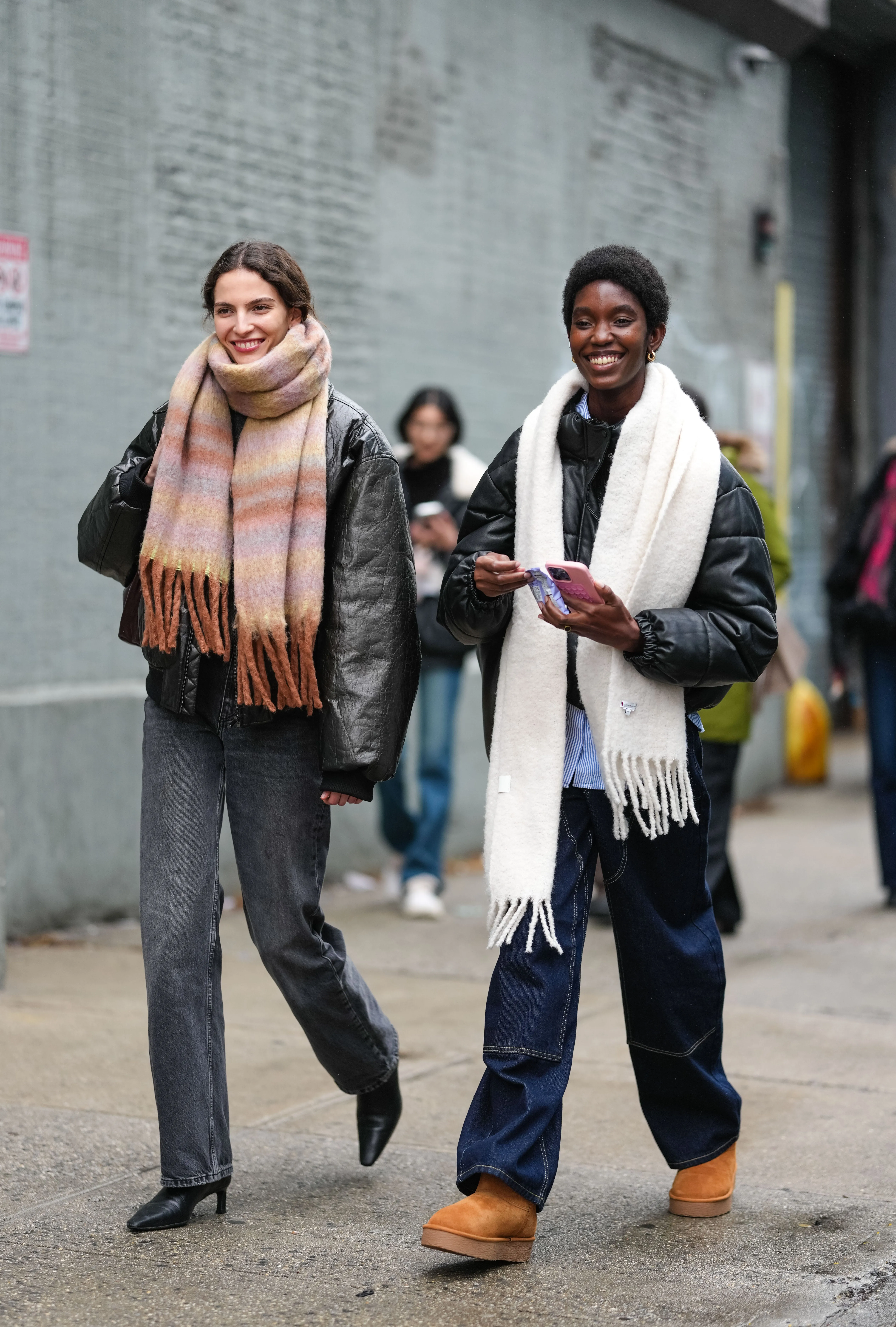 new york, new york february 06: a model wears a brown scarf, a black oversized jacket ; a model wears a white scarf, a puffer jacket, outside brandon maxwell, during new york fashion week, on february 06, 2025 in new york city. (photo by edward berthelot/getty images)