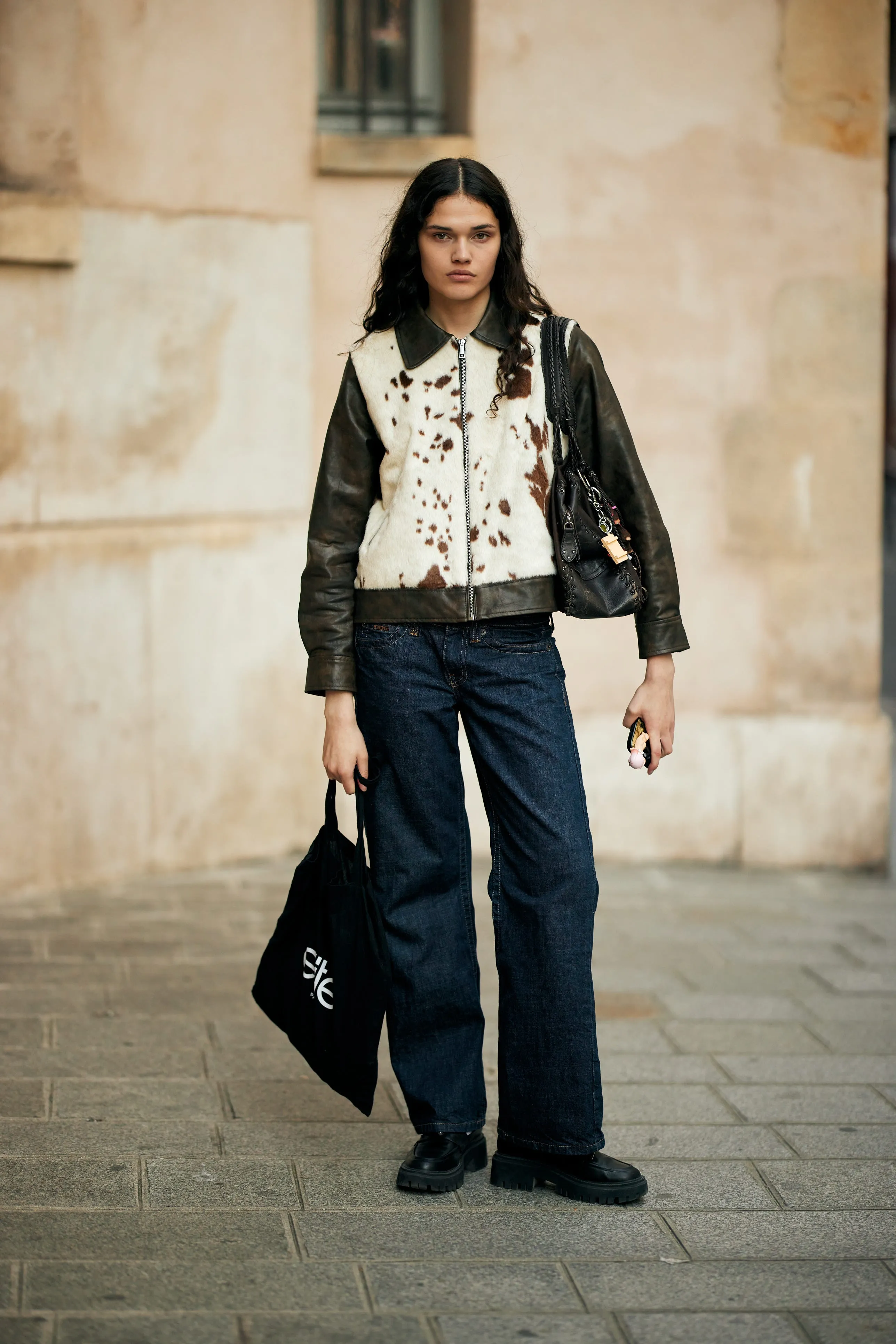 individual dressed in a unique outfit featuring a cowhide jacket and dark denim jeans