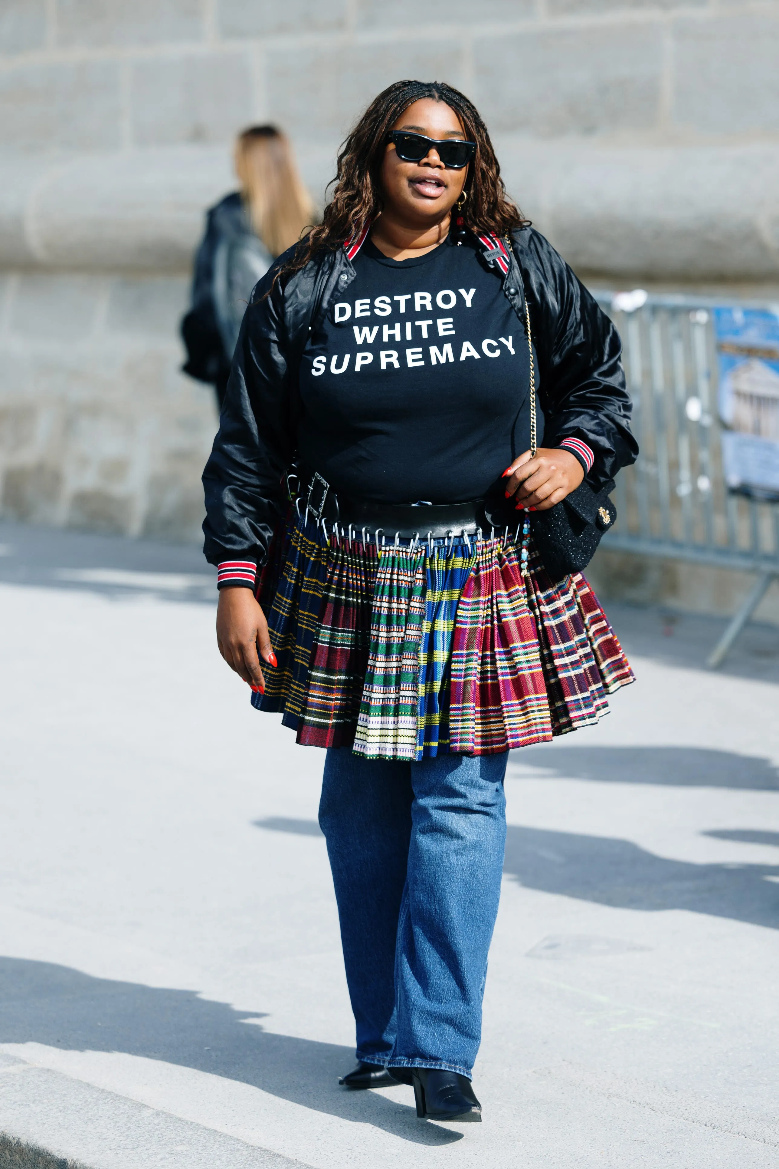 person wearing a statement tshirt and a skirt made of plaid fabric with denim jeans