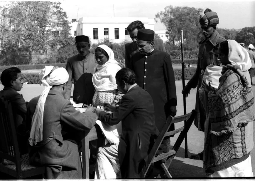 Outside the Town Hall Polling Booth, Delhi: A Polling Officer is seen issuing an identity Slip to a voter.