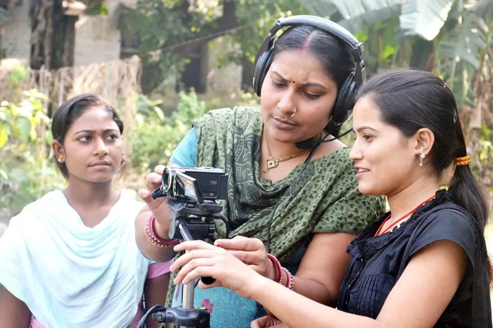 Fortnightly women reporters of Appan Samachar meet to decide on the topics to cover before different teams, comprising one reporter and another with a hand-held camera, pan out to different areas on a bicycle to interview villagers.