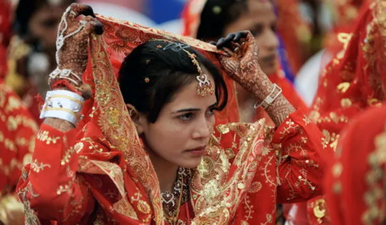 An Indian Muslim bride adjusts her veil as she waits for the start of a mass wedding in Ahmedabad on March 21, 2010. Some 201 Muslim couples participated in a mass wedding organised by The Gujarat Sarvajanik Welfare Trust. AFP PHOTO/ Sam PANTHAKY (Photo credit should read SAM PANTHAKY/AFP/Getty Images)