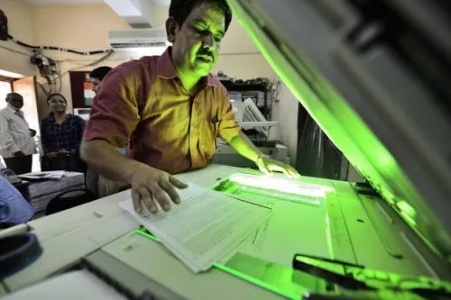 Image of a man photocopying a document on a white photocopying machine.