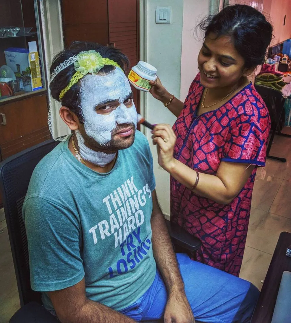 Sneha, helping her partner, Sourabh, put on a face mask. She put on their daughter’s hair bands on his head to prevent his hair from falling on his face.<br />
