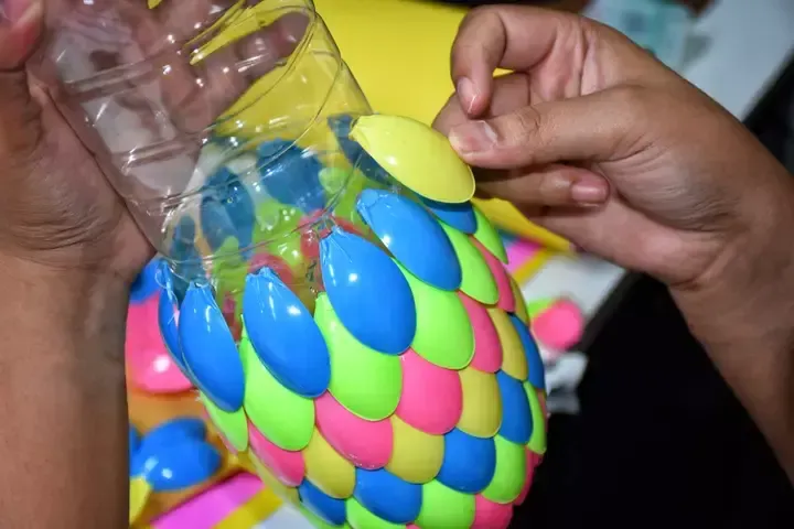 Gather a pile of clean plastic waste, such as old bottles, caps, and yoghurt pots, to make something creative out of them