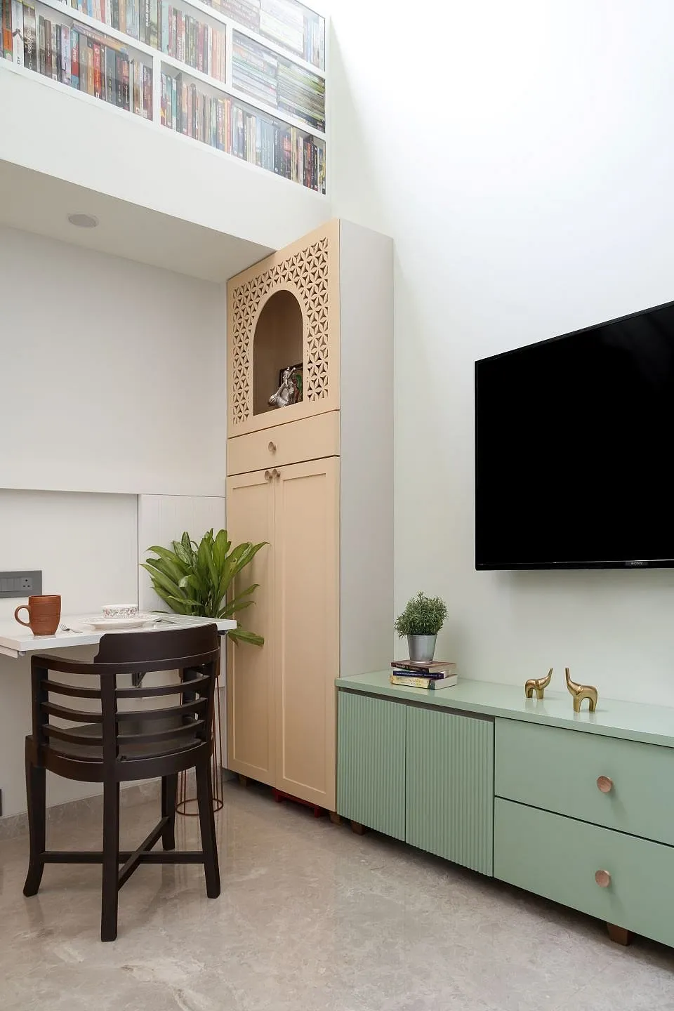 The Studio by Mindspace InteriorsA third of the 200sq ft was allotted to the compact kitchen and bathroom, and the rest is the living space. A skylight was introduced above the loft — this filled the previously dimly-lit apartment with natural light, adding freshness and warmth to the area. The minimal staircase leading to the loft occupies as little space as possible, and the space below it makes up for the wardrobe. The lower stairs contain additional storage, and the half railing bordering the loft provides space for Joshi's favourite books. The use of a pastel colour palette and natural wood was a unanimous decision; hence the walls are muted grey-white, with pops of colours introduced through furniture pieces. 