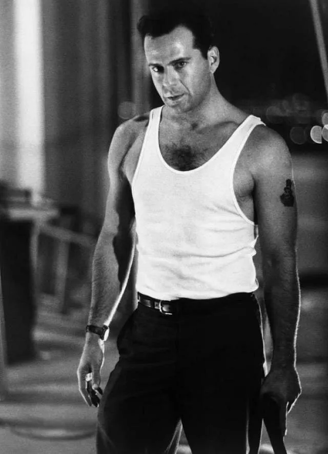 Bruce Willis wears a white tank top as John McClane in Die Hard (1988). Image: IMDB.com 