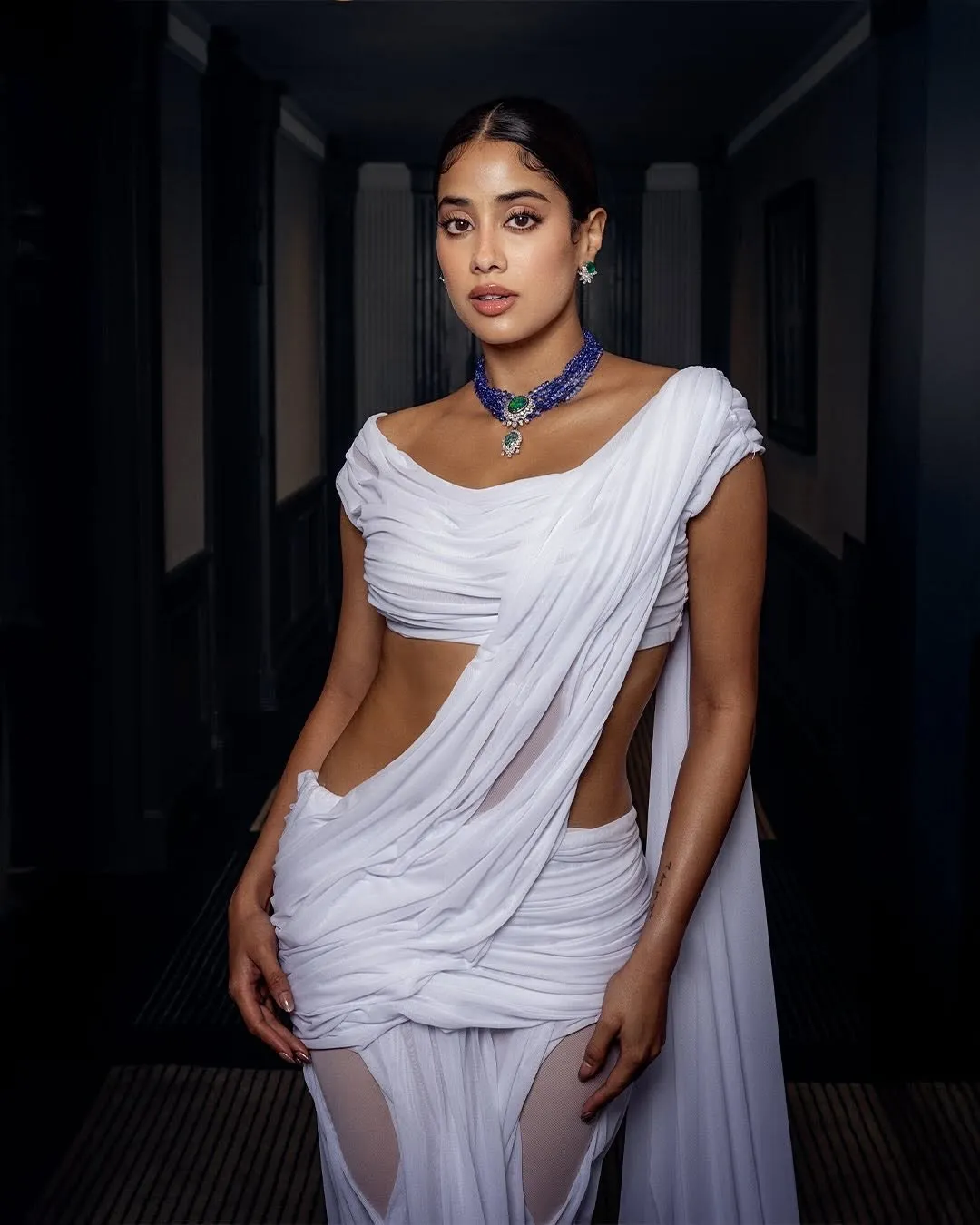 Janhvi Kapoor wearing a draped white sari-inspired gown by designer Di Petsa, representing modern interpretations of traditional Indian dress on the red carpet