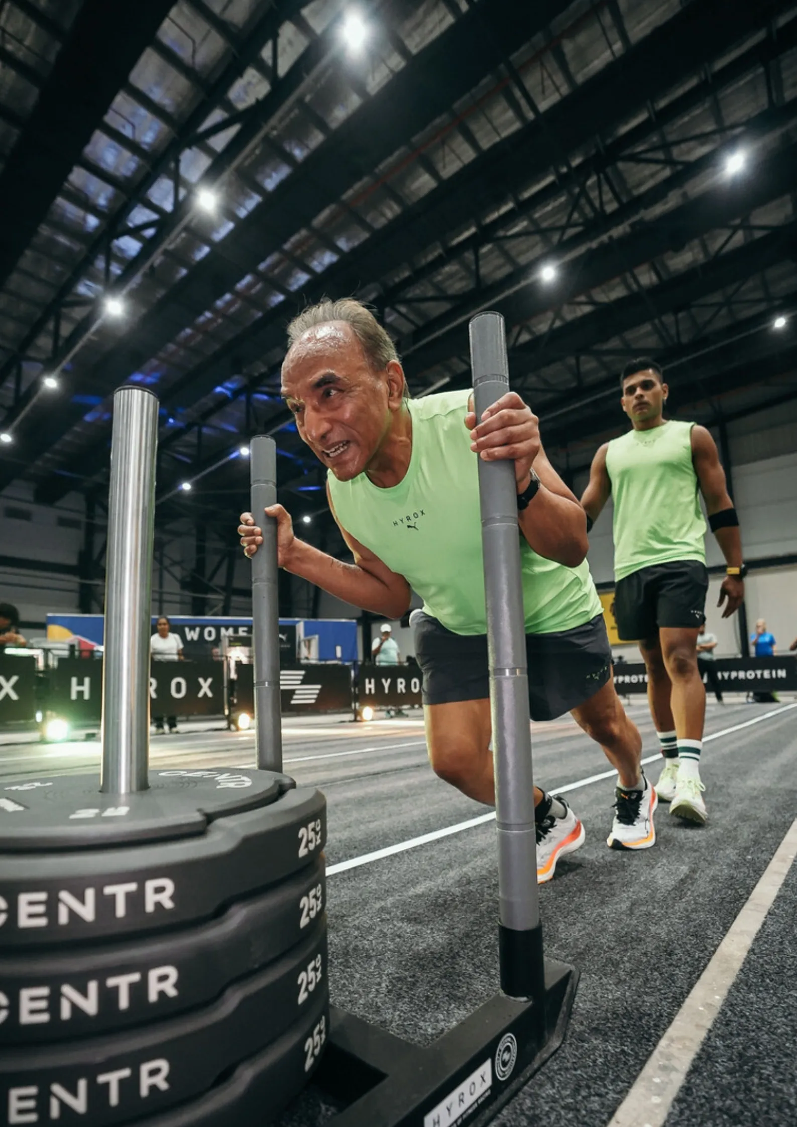 Older male athlete pushing a weighted sled during Hyrox India, showcasing the event’s focus on inclusive and competitive fitness