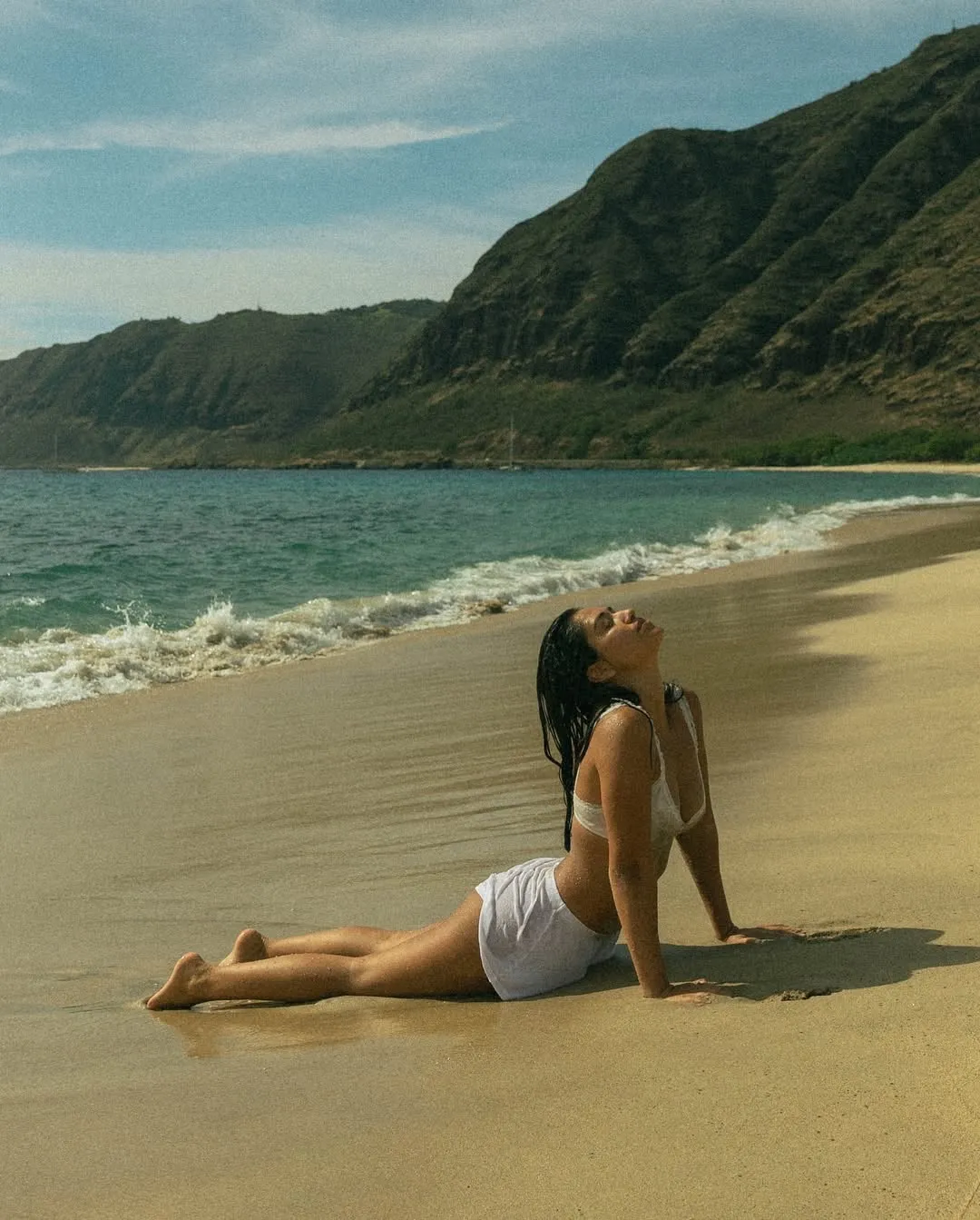 A woman is focusing in breathing while performing yoga asana Bhujangasana by the beach