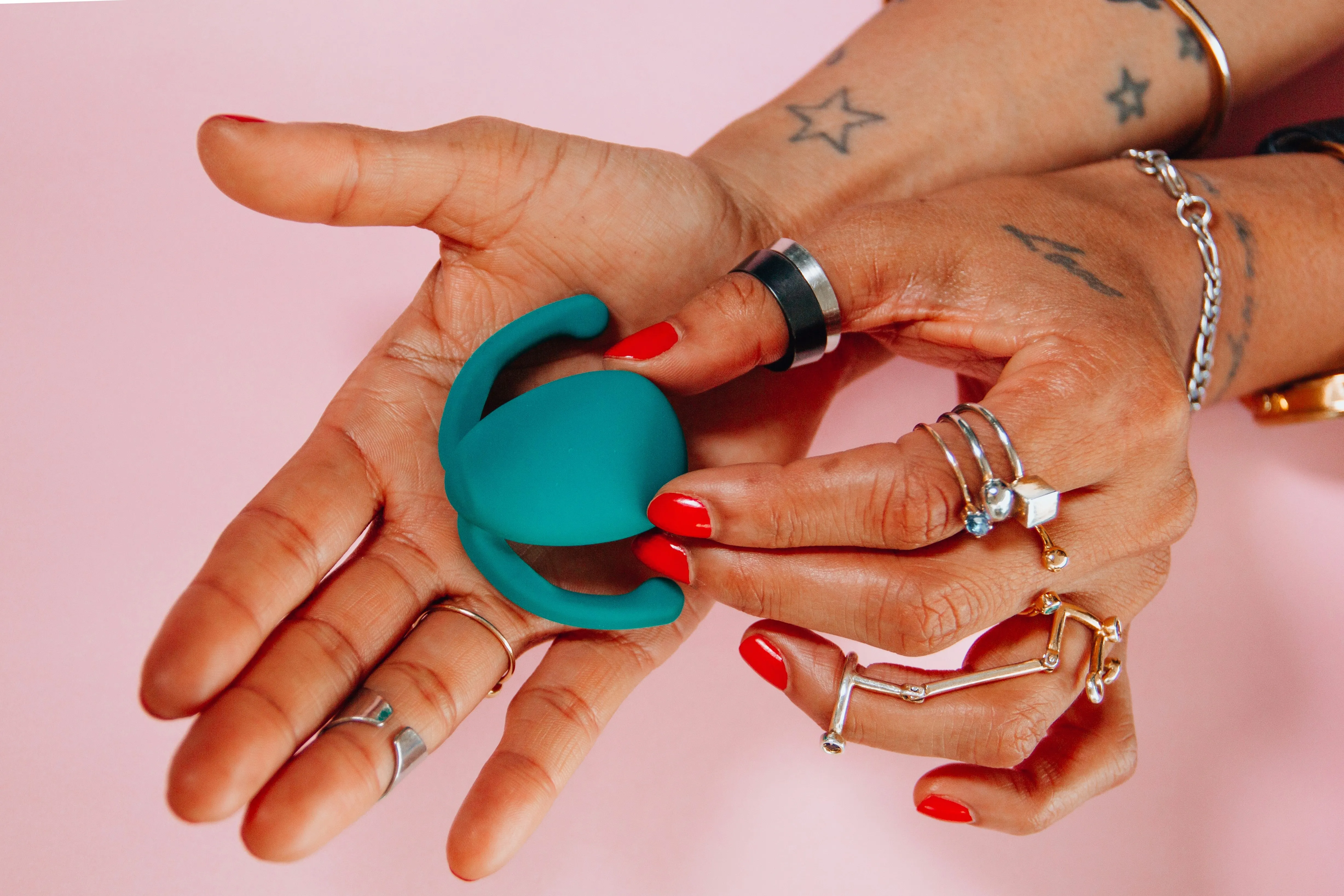 Close-up of tattooed  hands holding a teal  sex toy, representing  India’s growing sex  positivity and sexual  wellness culture