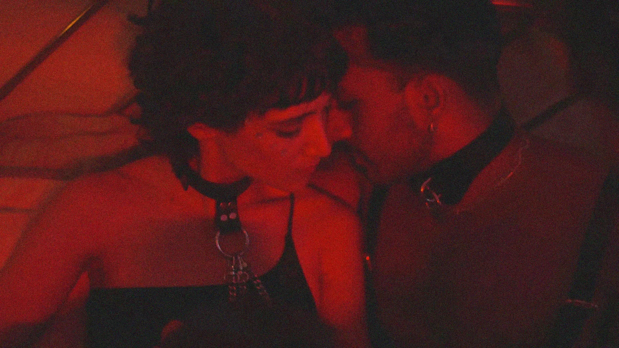 couple wearing  collars sharing an  intimate moment in  red lighting,  symbolising India’s  underground kink  subcultures and  BDSM community
