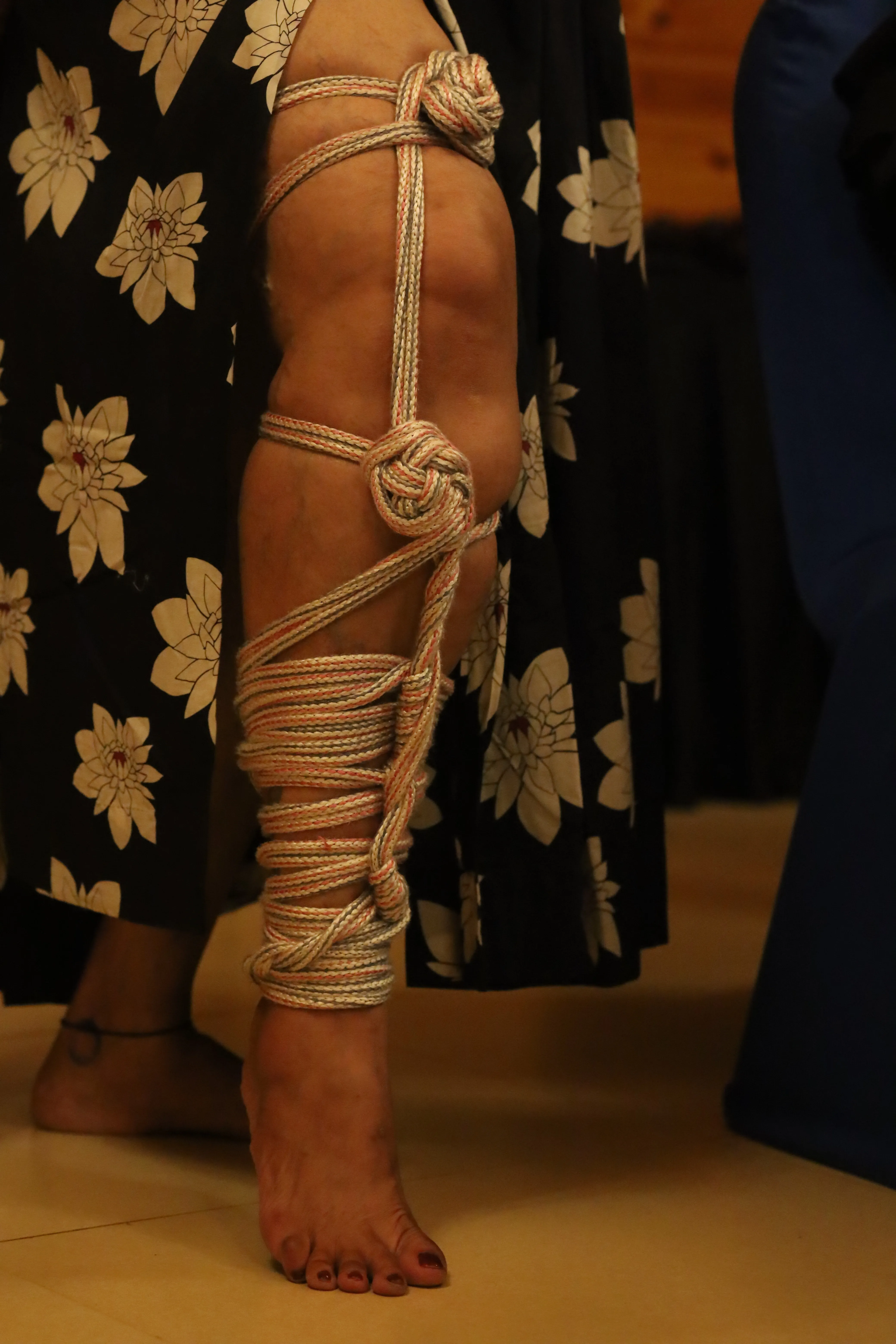 Detailed view of rope  bondage on a person’s leg, showcasing  traditional shibari  knots at an Indian  BDSM community  event