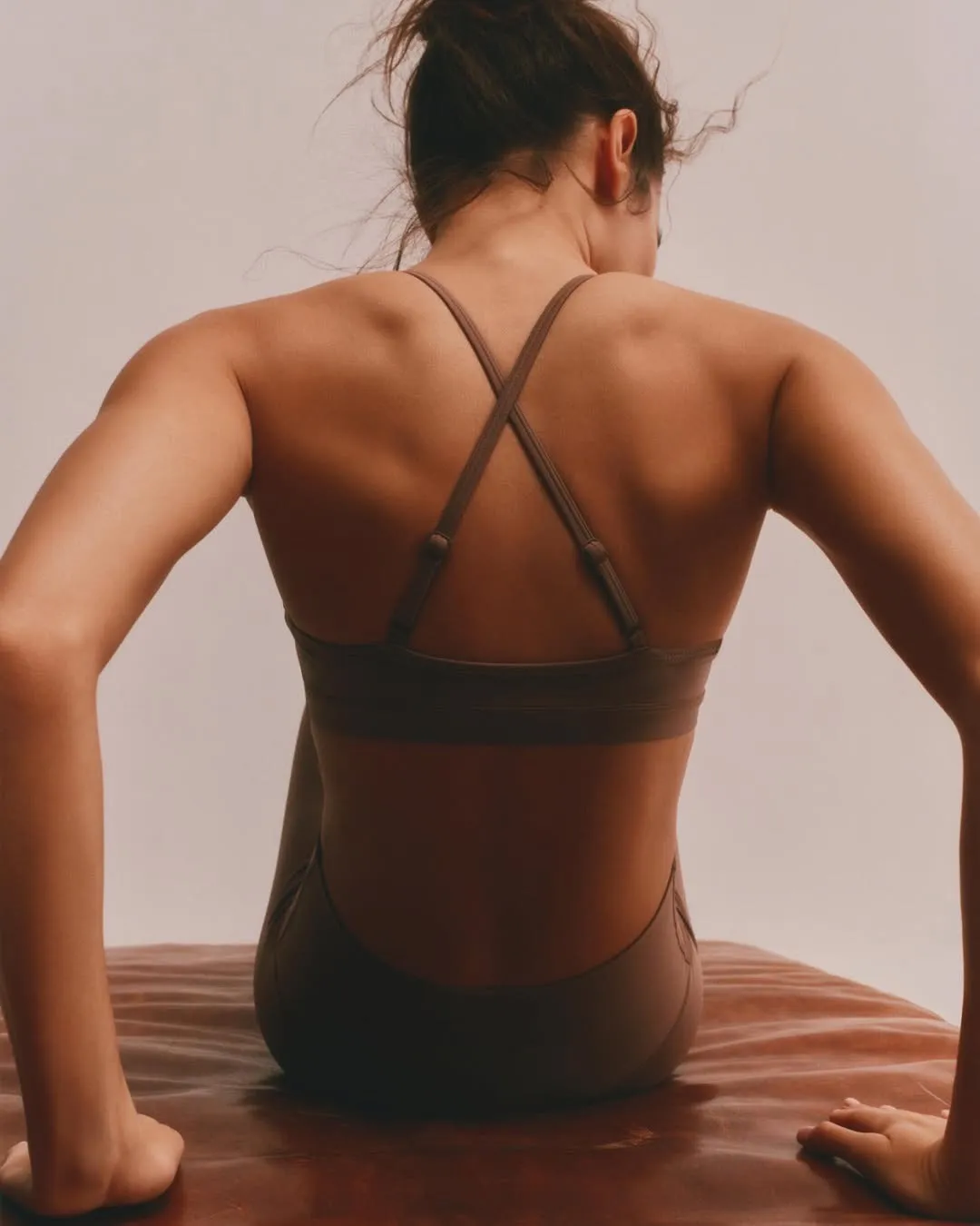 A woman in her brown-coloured athleisure wear performing yoga