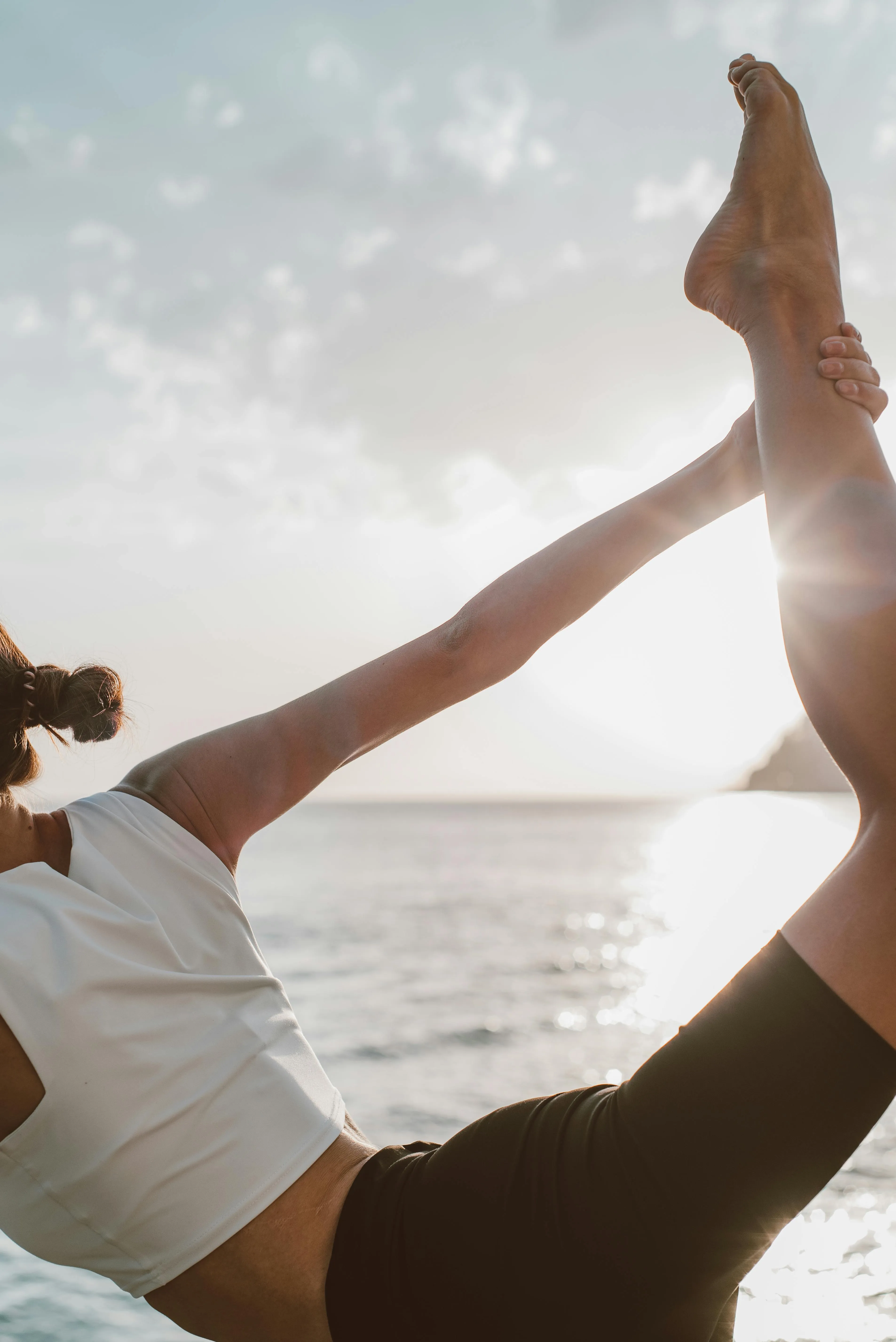 A woman performing yoga asanas by the beach