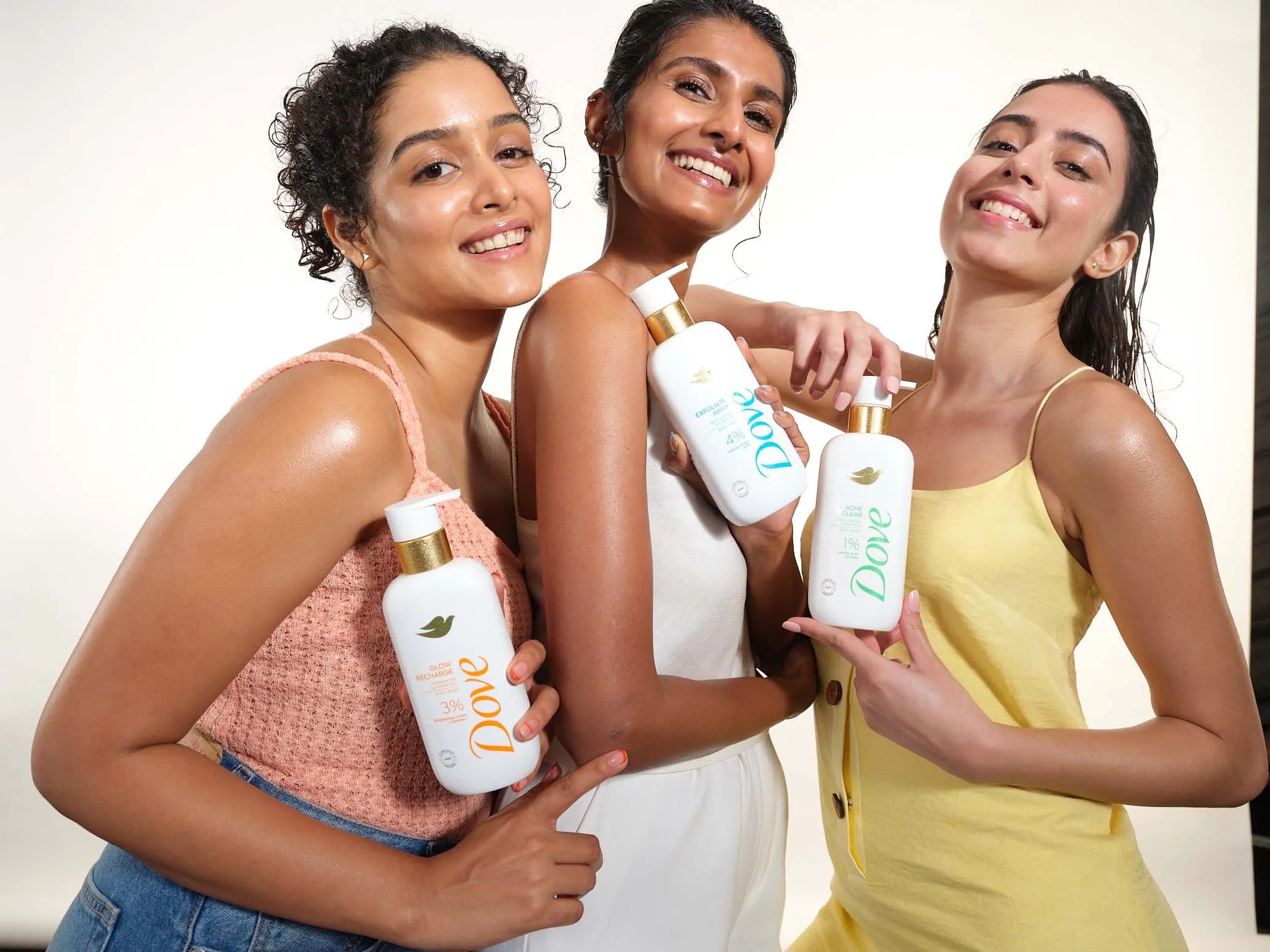 Three Indian women holding dove's body washes in their hand as part of their body care routine