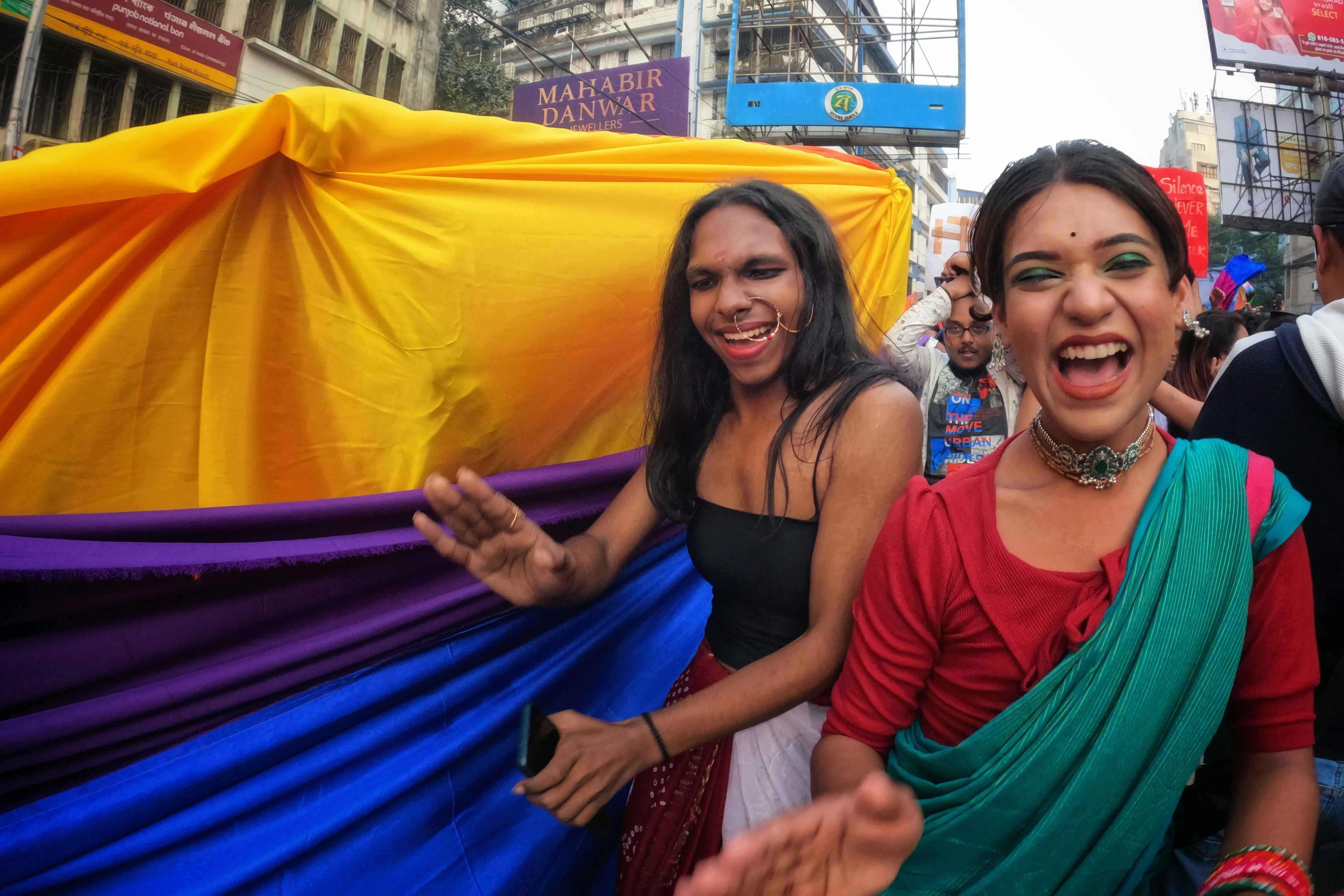 Two people in colourful attire dance at a parade for queer pride India, depicting drag culture India and queer visibility India