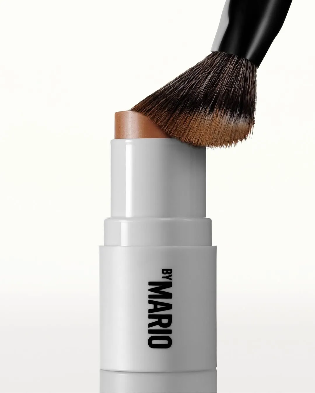 A cream contour stick from Makeup by Mario with a buffing brush