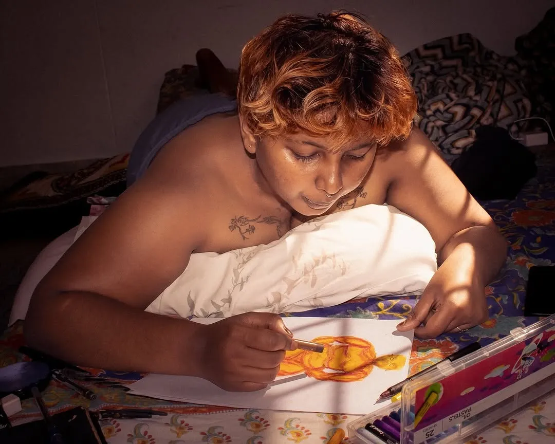 A person showing transmasculine identity paints as they lay down to depict gender expression in India, becoming a part of Indian LGBTQ stories