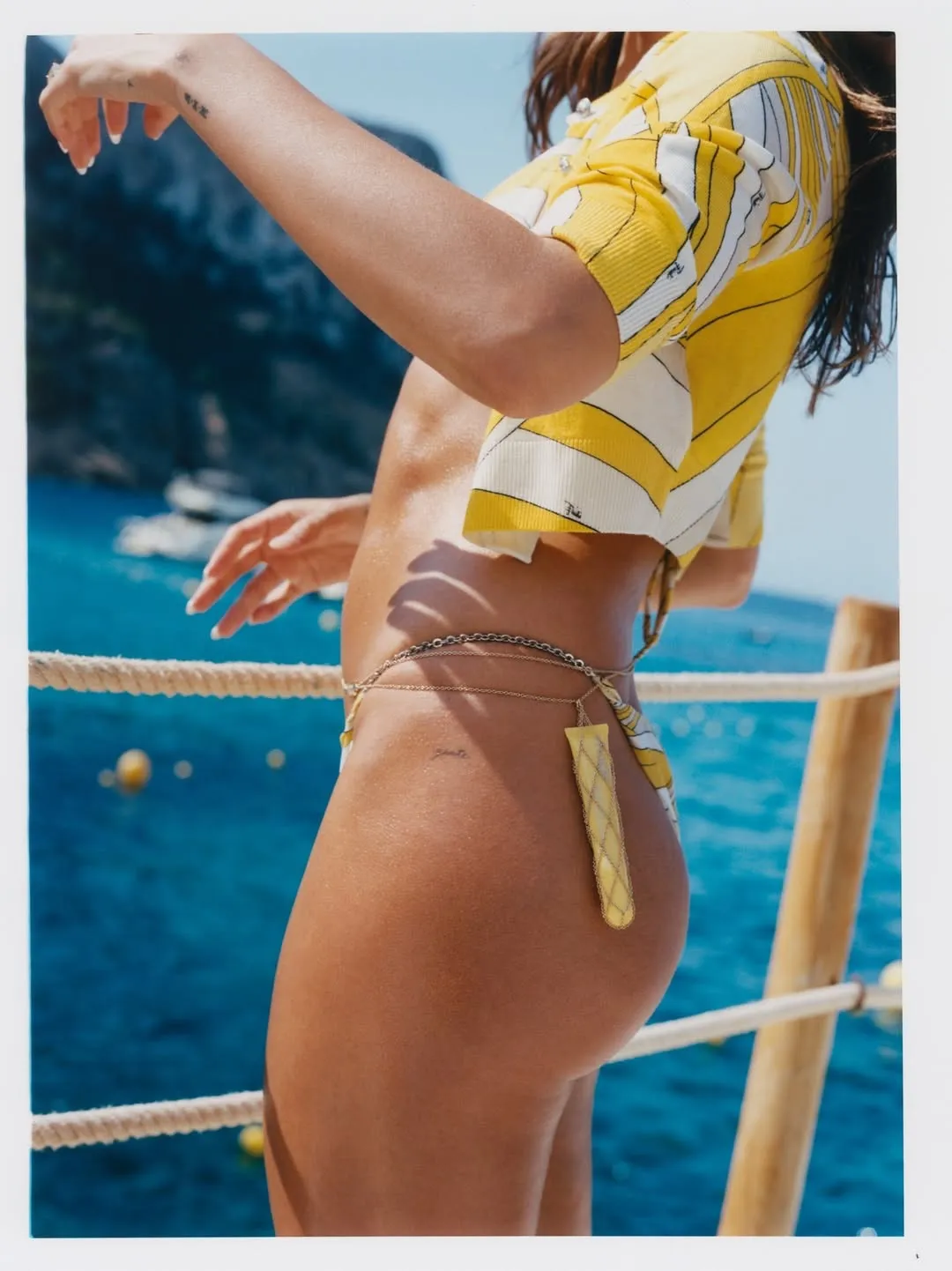 A picture of a woman at the beach in yellow apparel and a wait chain with a lip balm