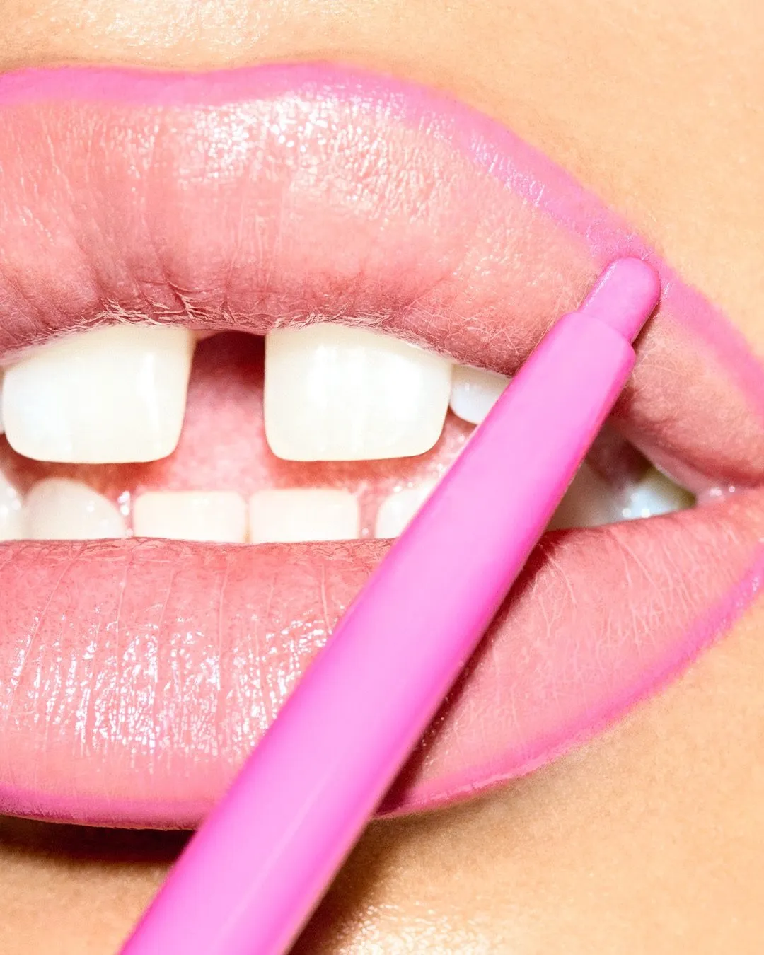 A woman lining her lips with a bubblegum pink lip liner