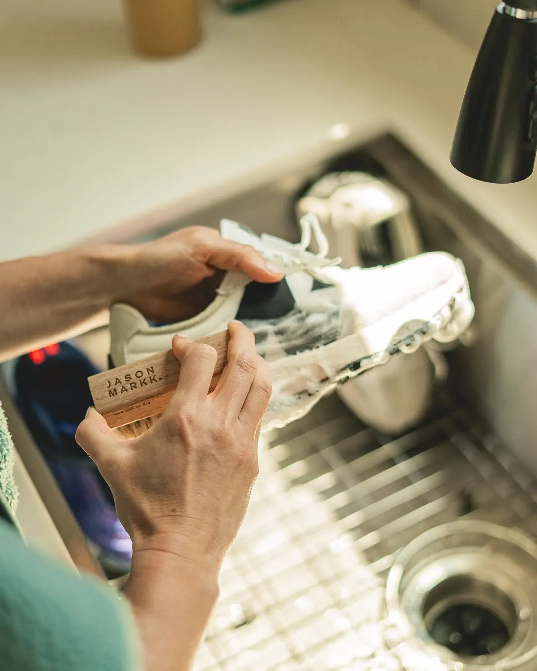 A man scrubbing his sneakers with a white shoe cleaner brush