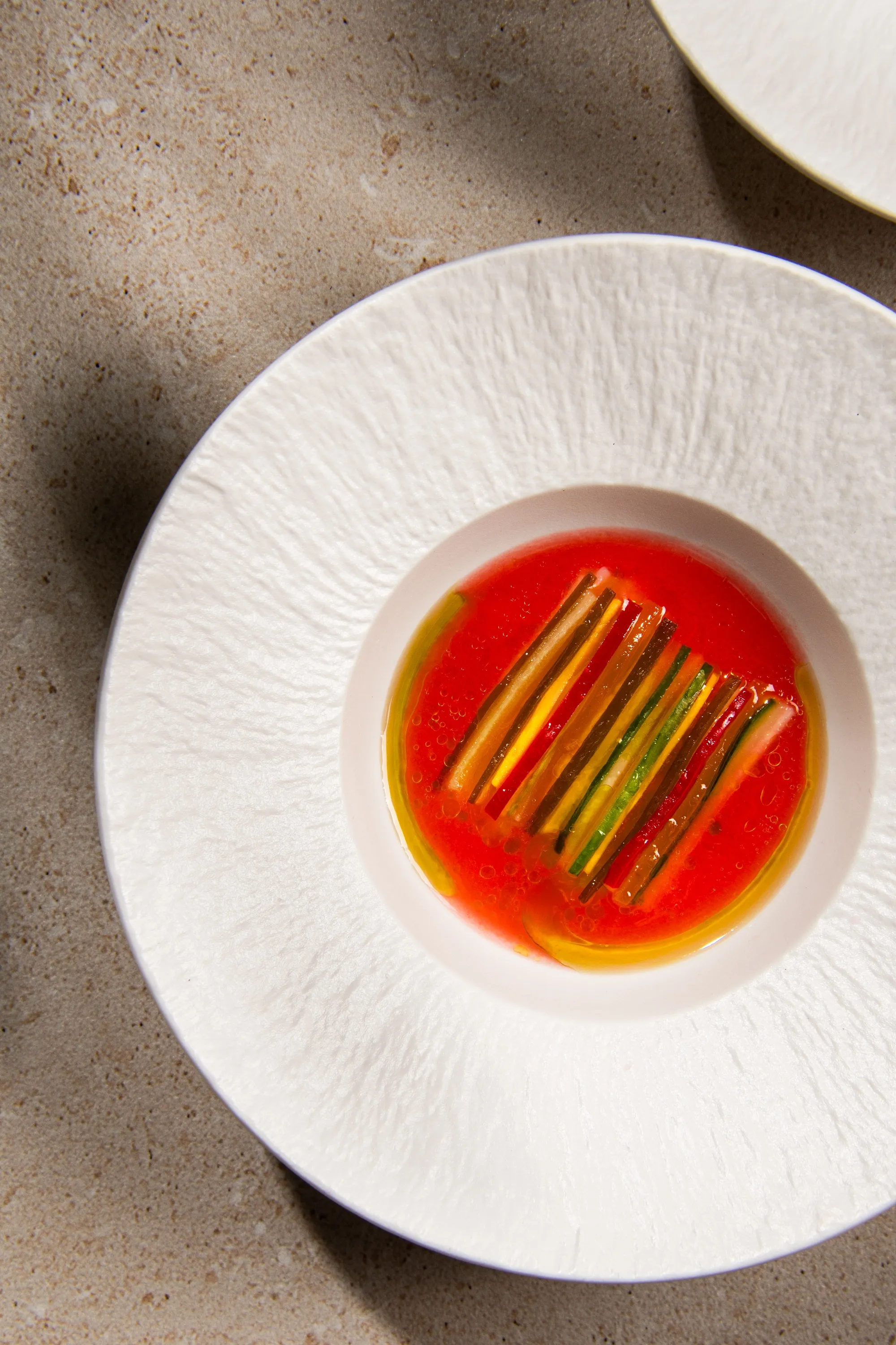 A picture of veggies placed in a sauce and served artfully in a fancy plate to show vegetarian Michelin restaurants India could also be a concept, which has ample vegetarian fine dining India