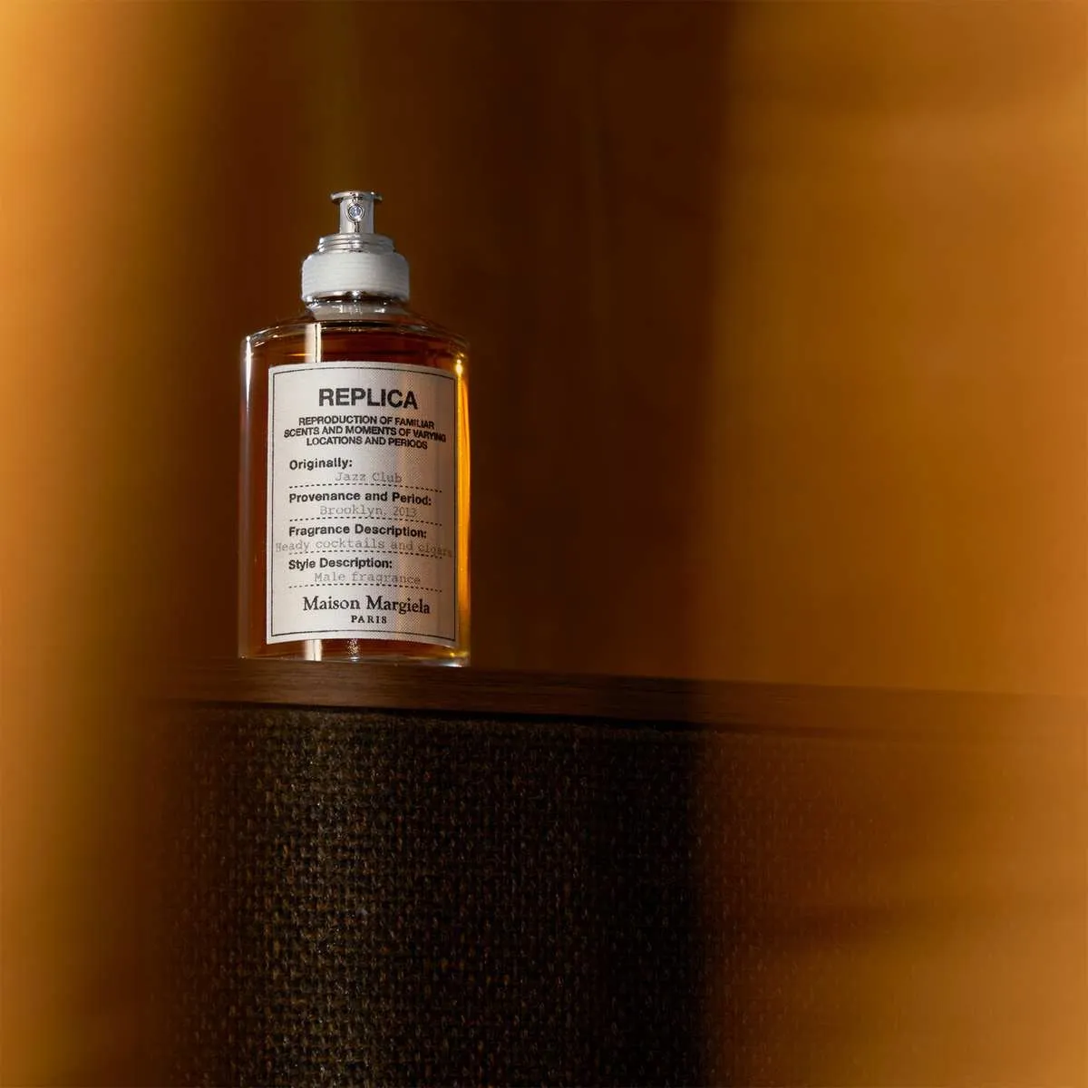 Maison Mariela Replica vanilla perfume placed on a wooden table against golden light